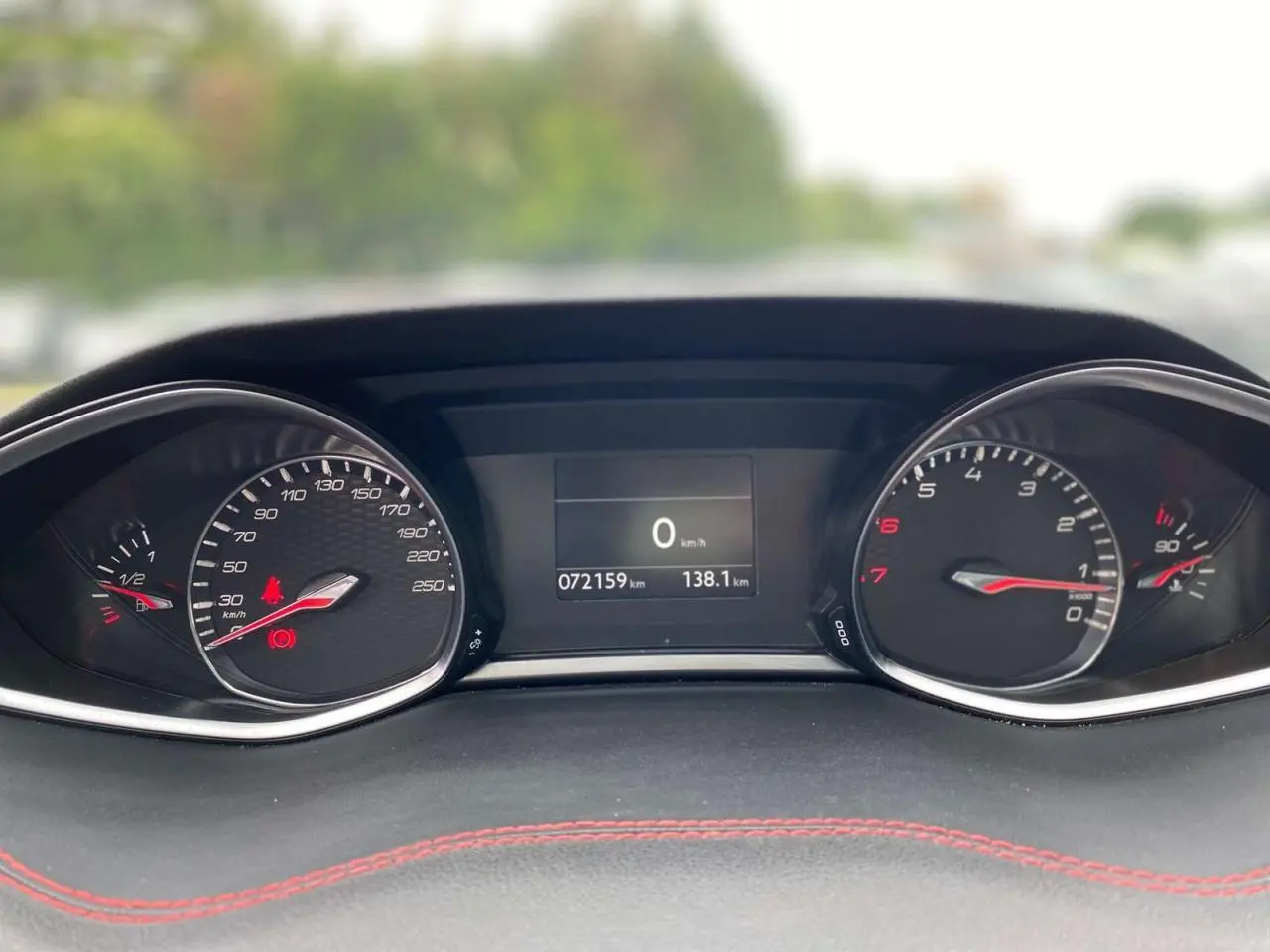 Gros plan sur le tableau de bord de la Peugeot 308 GTi 2016 avec compteurs analogiques et écran digital central.