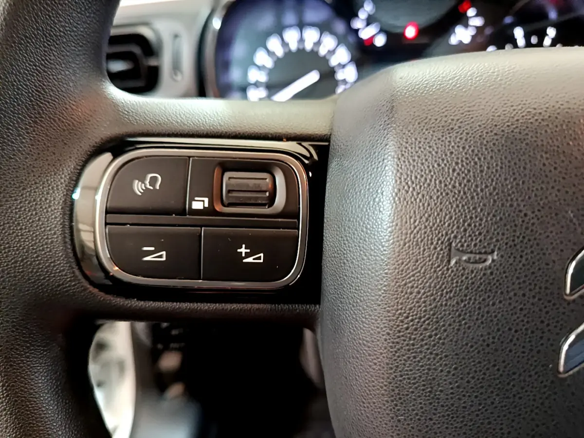 Gros plan sur les commandes à gauche du volant noir de la Citroën C3 PureTech 68 BVM Feel 2018.