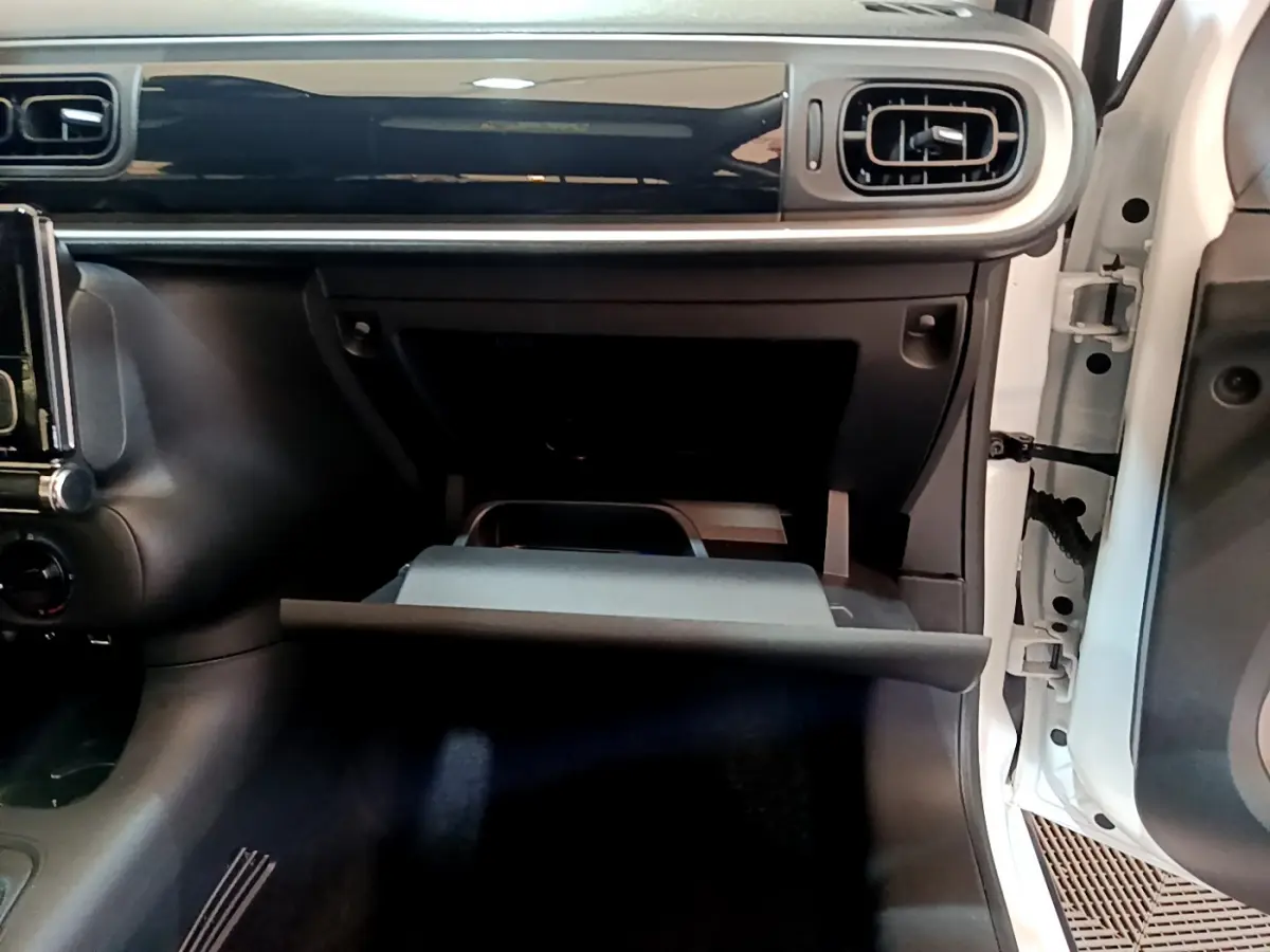 Intérieur de la Citroën C3 blanc 2018, vue côté passager avec boîte à gants ouverte et tableau de bord noir brillant.