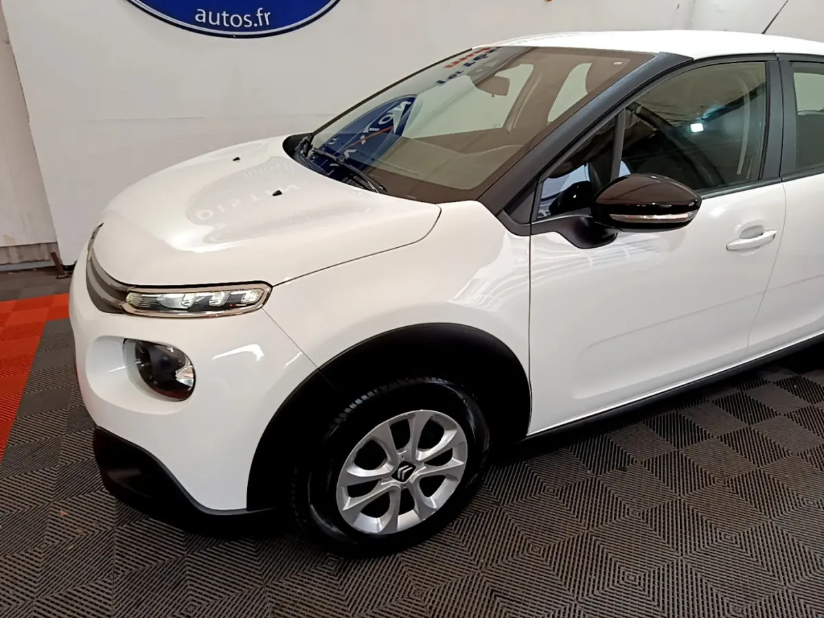 Vue 3/4 avant gauche d'une Citroën C3 blanche avec rétroviseurs noirs et jantes alliage argentées.