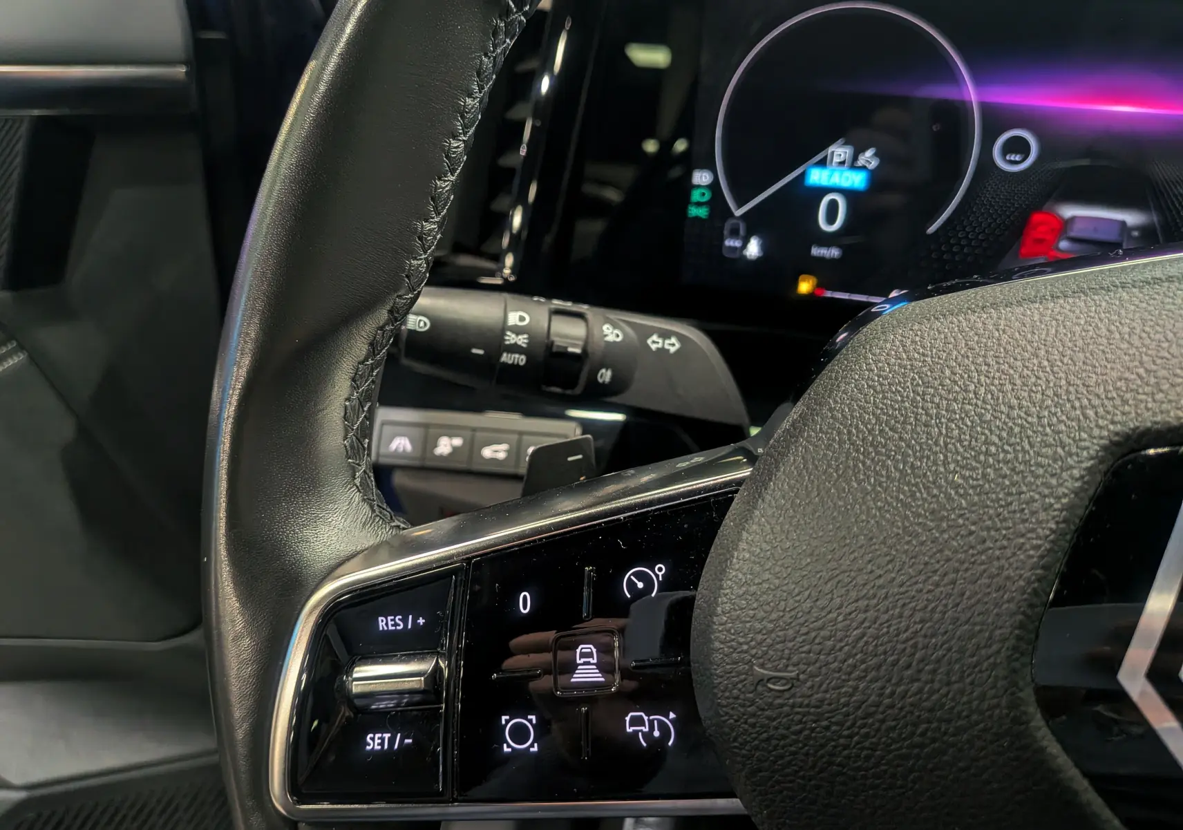 Gros plan sur le volant cuir noir du Renault Austral E-Tech Hybrid 2024, avec commandes intégrées et tableau de bord numérique.