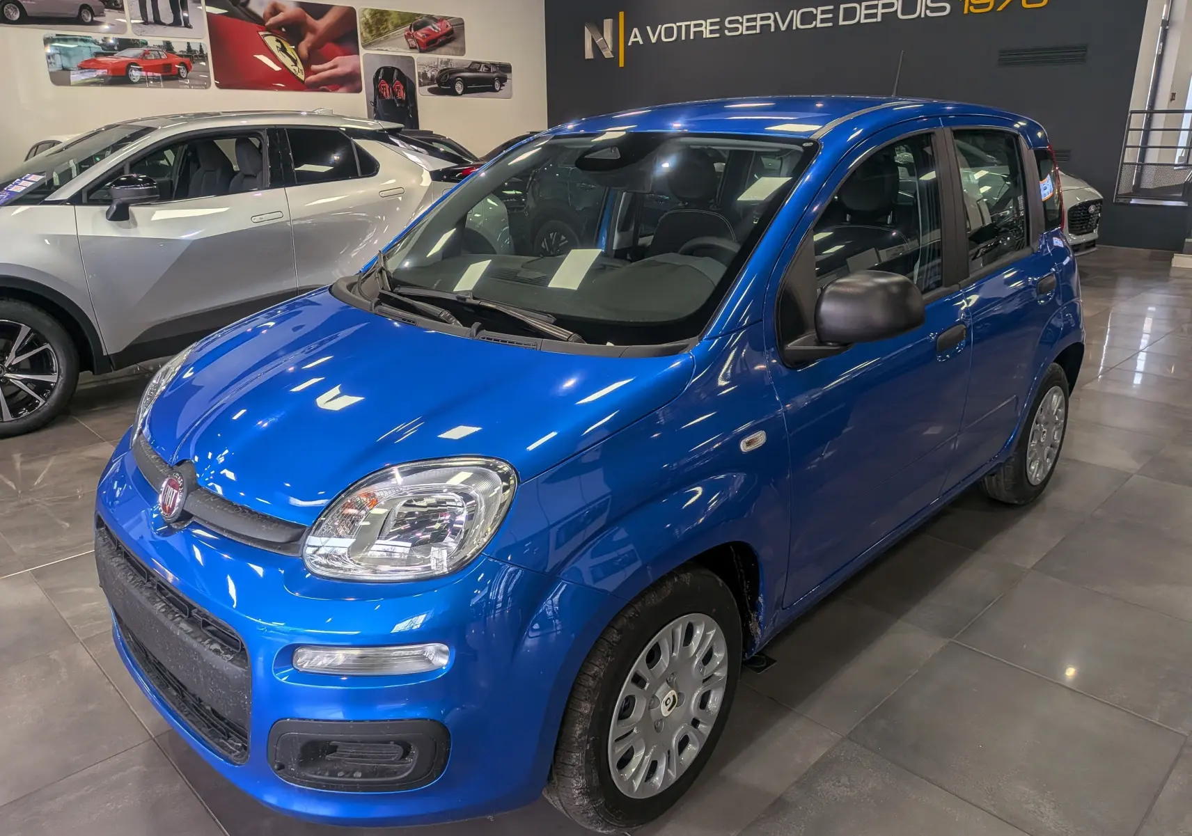 Vue 3/4 avant droite d'une FIAT Panda 1.0 Hybrid 2025 en Bleu Italia avec jantes acier et rétroviseurs noirs.