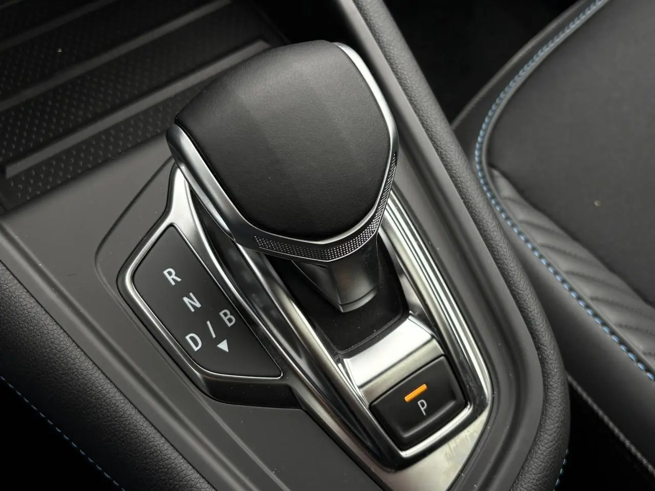 Le levier de vitesses automatique noir et chrome du Renault Captur E-Tech avec surpiqûres bleues sur la console.