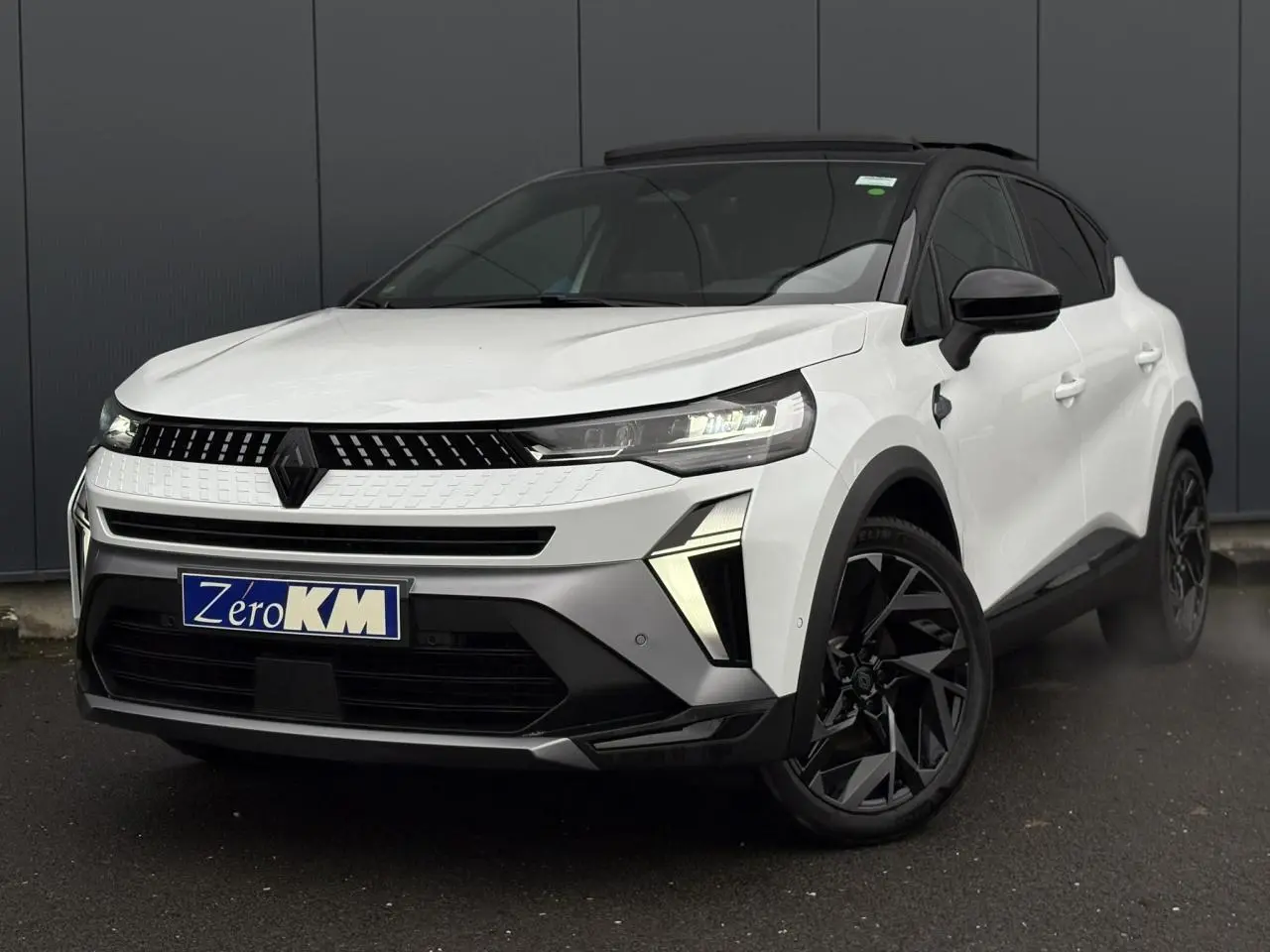 Vue 3/4 avant droit du Renault Captur blanc nacré avec toit noir et jantes noires distinctives.