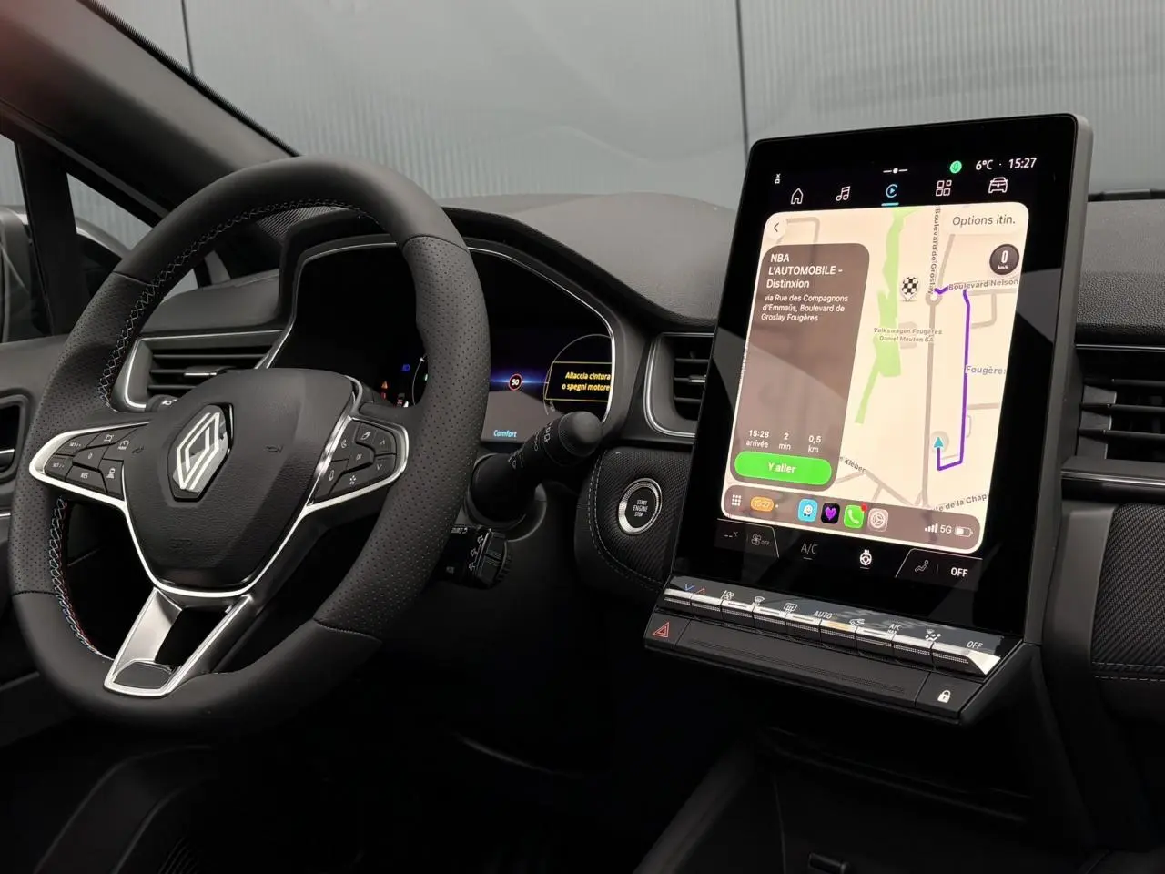 Vue intérieure du tableau de bord du Renault Captur 2025, volant avec logo et écran tactile vertical affichant la navigation.