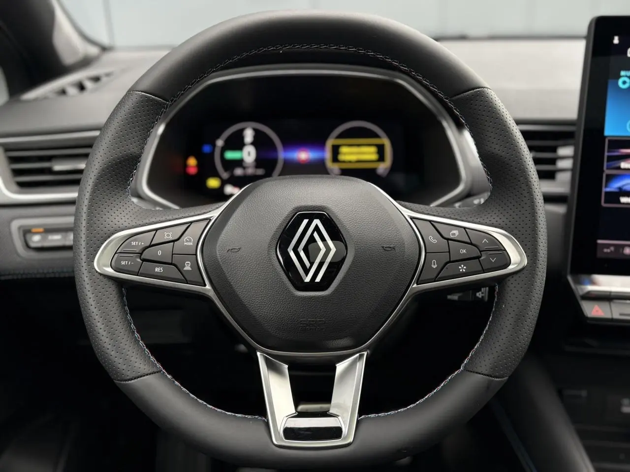 Vue rapprochée du volant noir perforé du Renault Captur 2025 avec logo central et commandes intégrées.