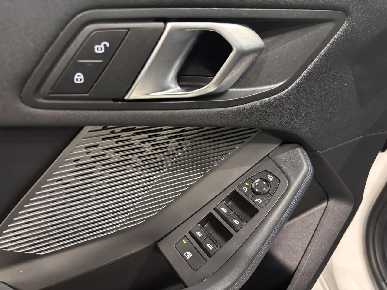 Détail de la porte avant gauche de la BMW Série 1 blanche, avec commandes de vitres et poignée argentée.