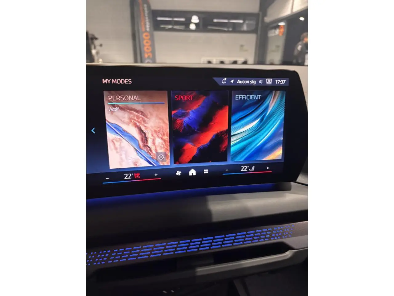 Écran central tactile affichant les modes de conduite Personal, Sport et Efficient dans une BMW Série 1 blanche.