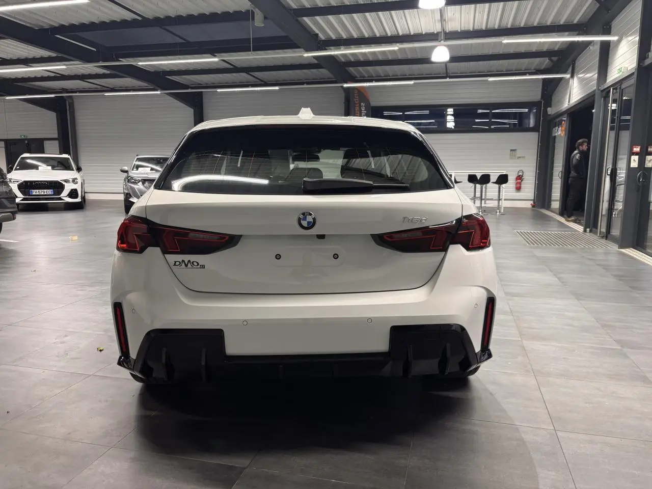 Vue arrière d'une BMW Série 1 blanche 118D M Sport 2025, avec diffuseur noir et feux LED distinctifs.