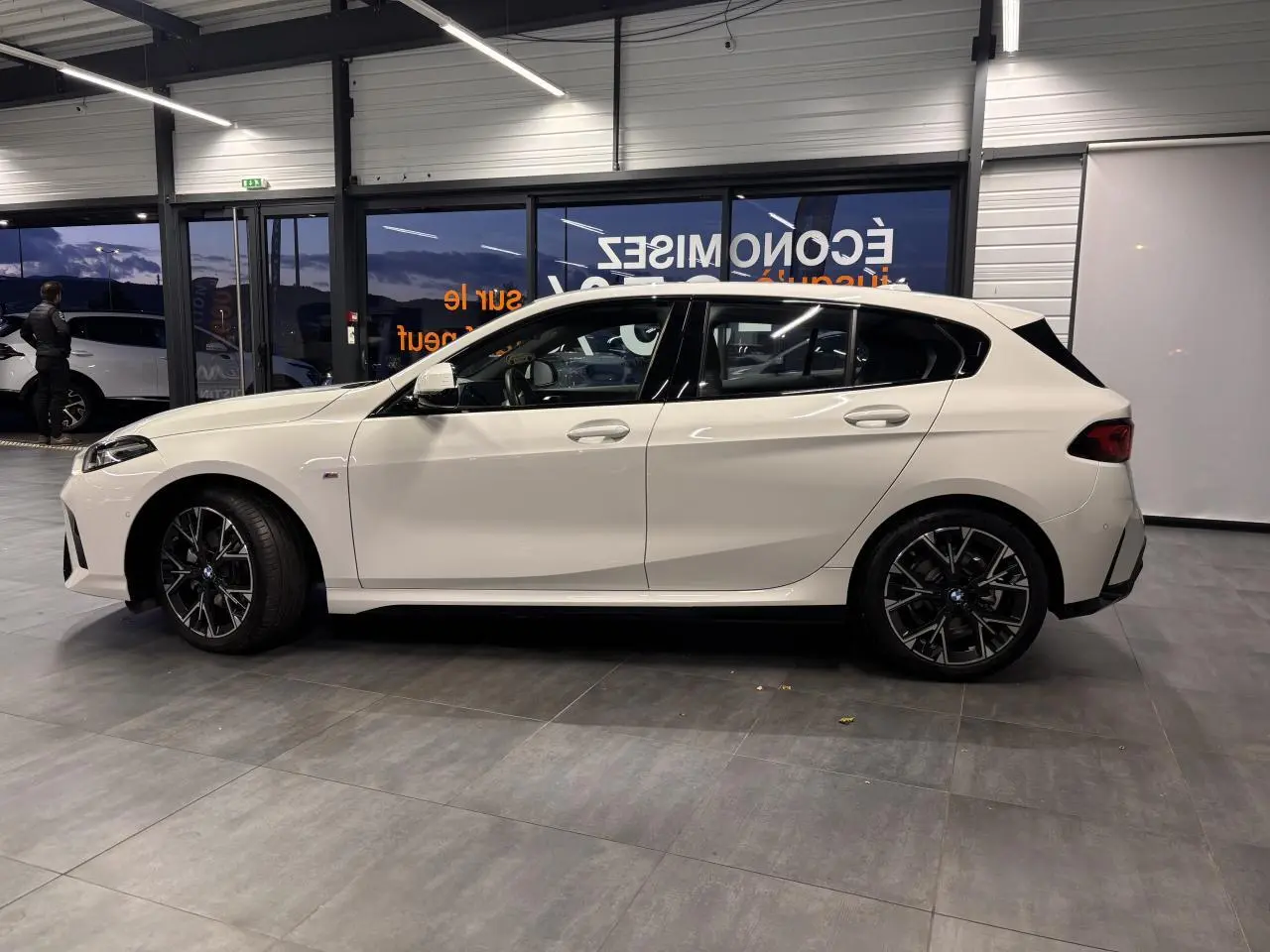 Vue de profil côté gauche d'une BMW Série 1 blanche 118D M Sport avec jantes alliage 18 pouces bicolores.