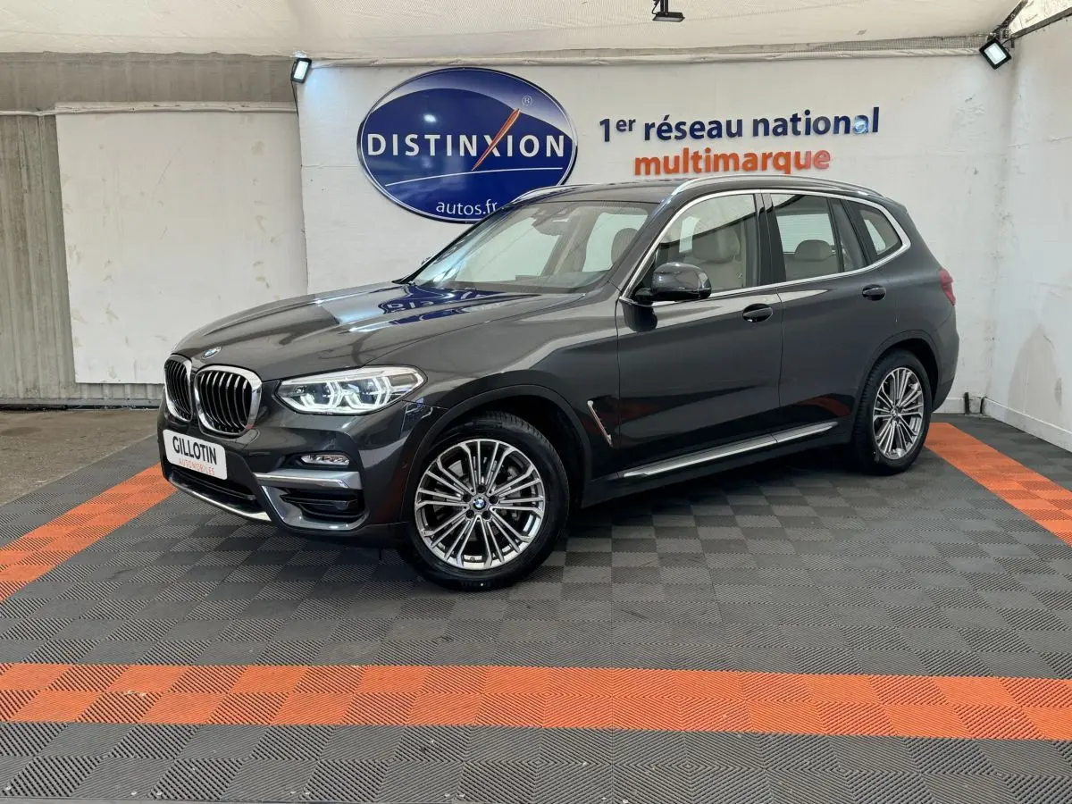 BMW X3 xDrive30d gris foncé vue 3/4 avant droit, avec phares LED allumés dans un showroom.