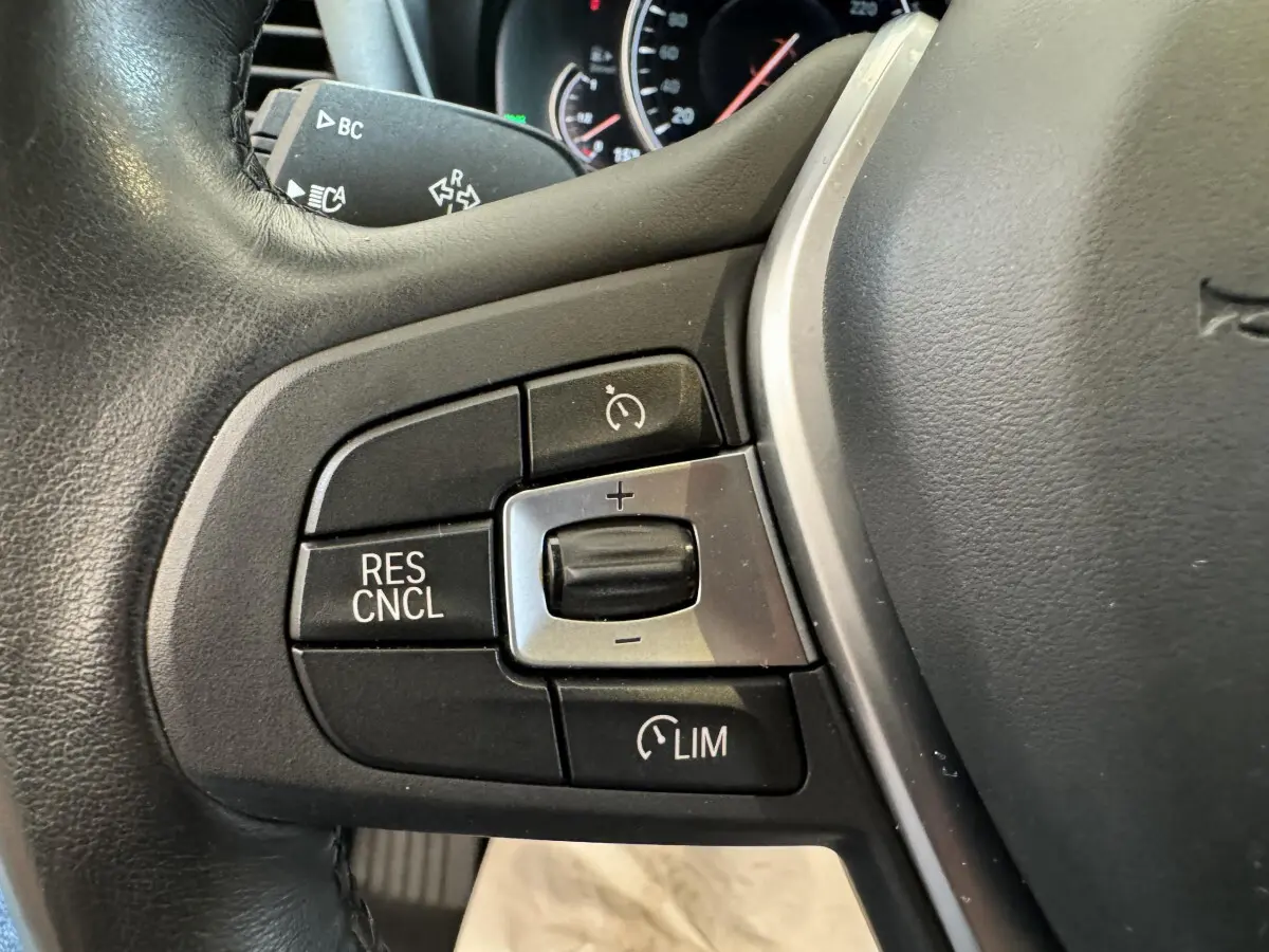 Gros plan sur les commandes de régulateur de vitesse au volant cuir noir du BMW X3 xDrive30d gris foncé de 2018.