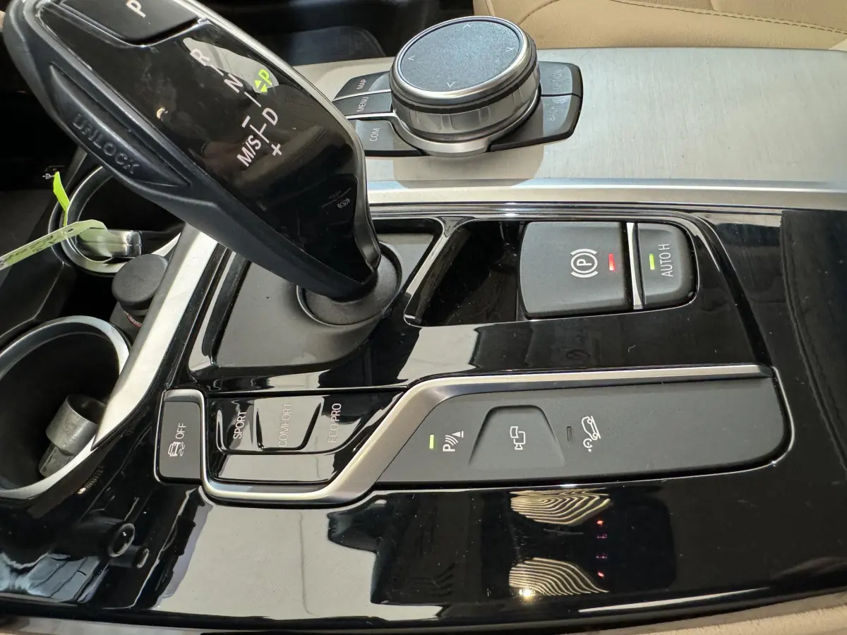 Gros plan sur la console centrale noire brillante du BMW X3 xDrive30d 2018 avec levier de vitesse automatique et boutons de contrôle.