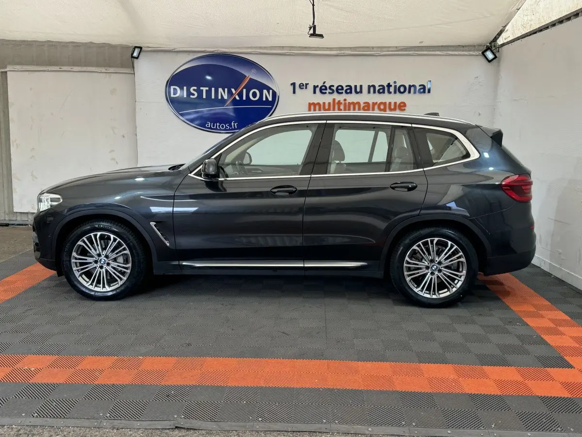 BMW X3 xDrive30d gris foncé vu de profil côté gauche, avec jantes alliage et rails de toit chromés.