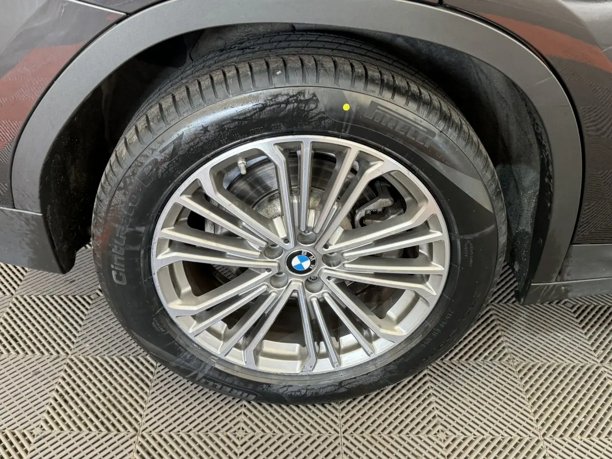 Gros plan sur la roue avant gauche d’un BMW X3 gris foncé, mettant en valeur la jante alliage multi-branches et le pneu.