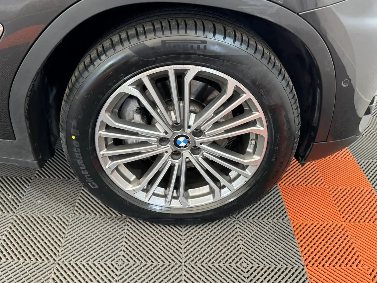 Gros plan sur la roue avant droite avec jante alliage argentée et pneu Pirelli sur BMW X3 gris foncé.