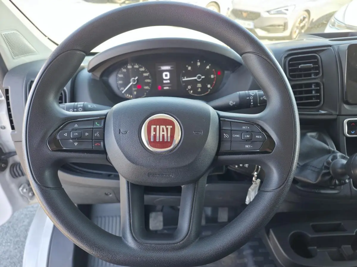 Vue intérieure centrée sur le volant noir du Fiat Ducato Fourgon blanc avec tableau de bord et levier de vitesses manuel.
