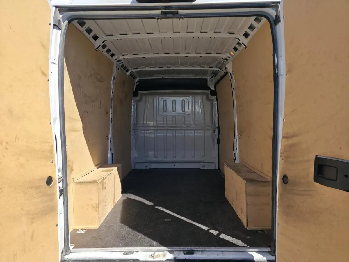 Vue intérieure arrière du fourgon FIAT Ducato blanc, montrant l'espace de chargement vide avec parois en bois.
