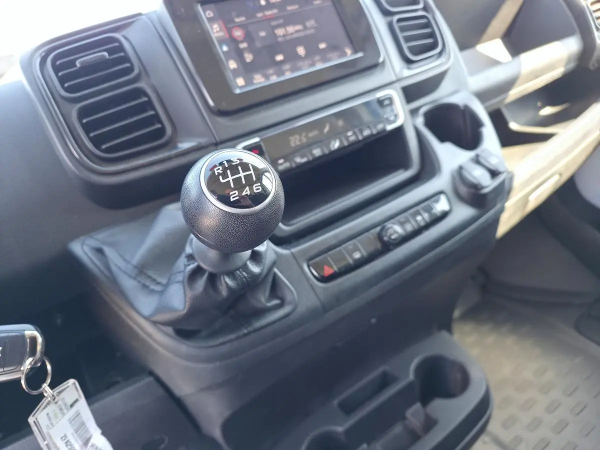 Gros plan sur le levier de vitesses manuel et la console centrale du Fiat Ducato Fourgon blanc, intérieur fonctionnel et moderne.