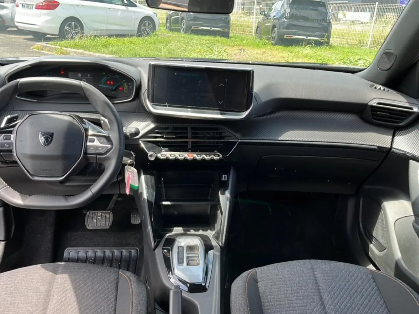 Intérieur Peugeot 2008 1.2 hybrid 2025 vu de face, tableau de bord noir avec écran tactile central et volant compact.