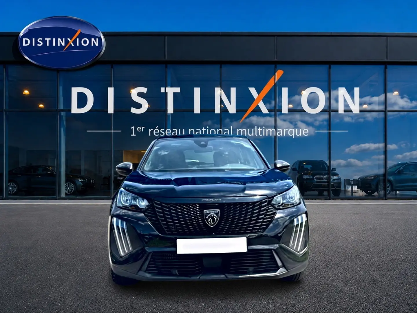 Vue frontale d'un Peugeot 2008 noir 2025 avec calandre distinctive et feux LED verticaux, devant une vitrine Distinxion.