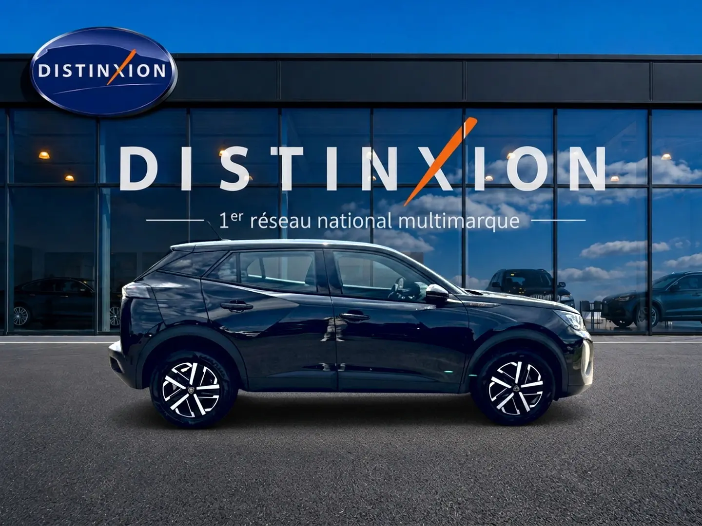 Profil côté gauche d’un Peugeot 2008 noir 2025 avec jantes alliage et vitres teintées devant un bâtiment vitré Distinxion.
