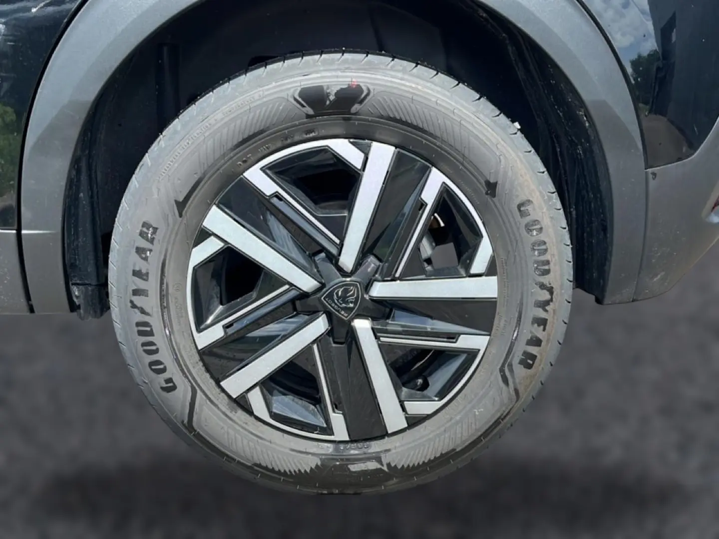 Gros plan sur la roue avant gauche noire avec jante alliage bicolore du Peugeot 2008 1.2 hybrid 145 style e-dcs6 2025.