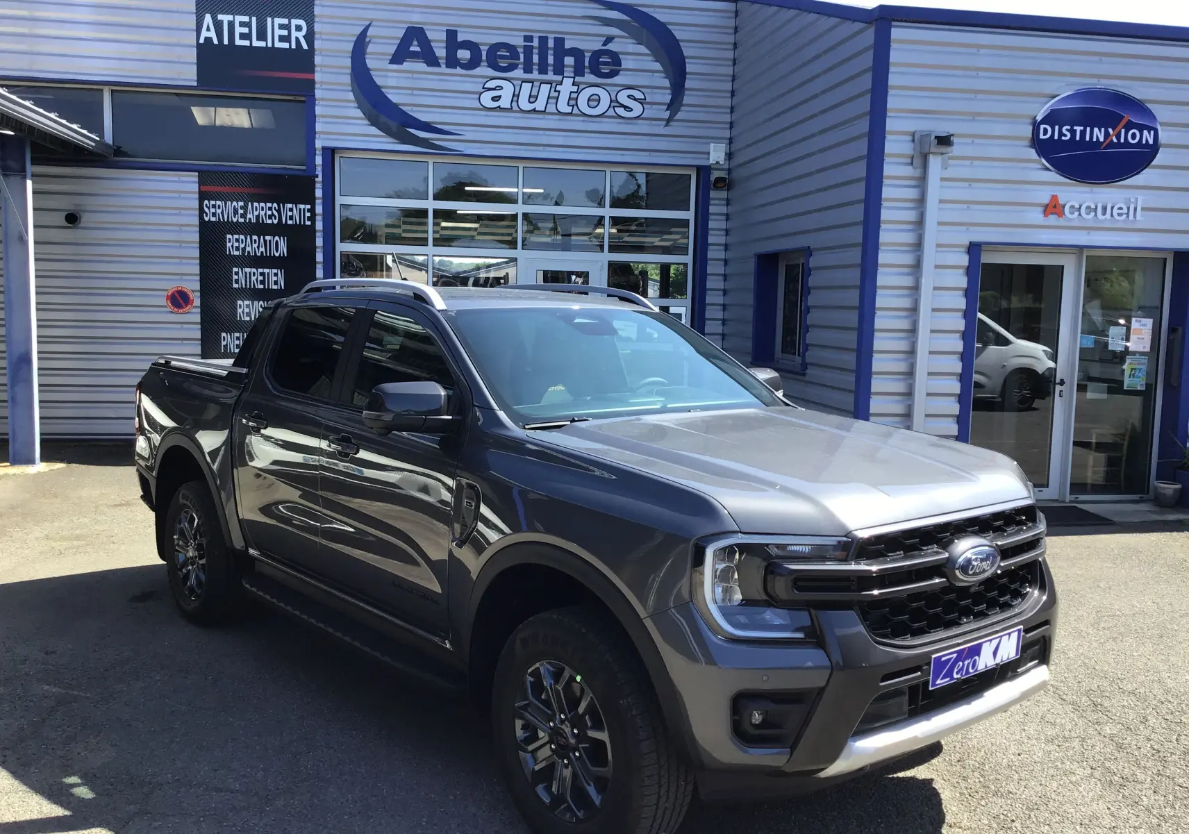 Ford Ranger Double Cabine gris carbone vu en 3/4 avant droit devant un garage Abeilhé Autos.