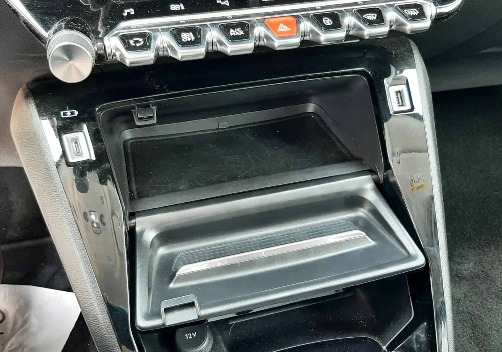 Gros plan sur la console centrale noire du Peugeot 2008 2022, avec boutons de commande et prise 12V visible