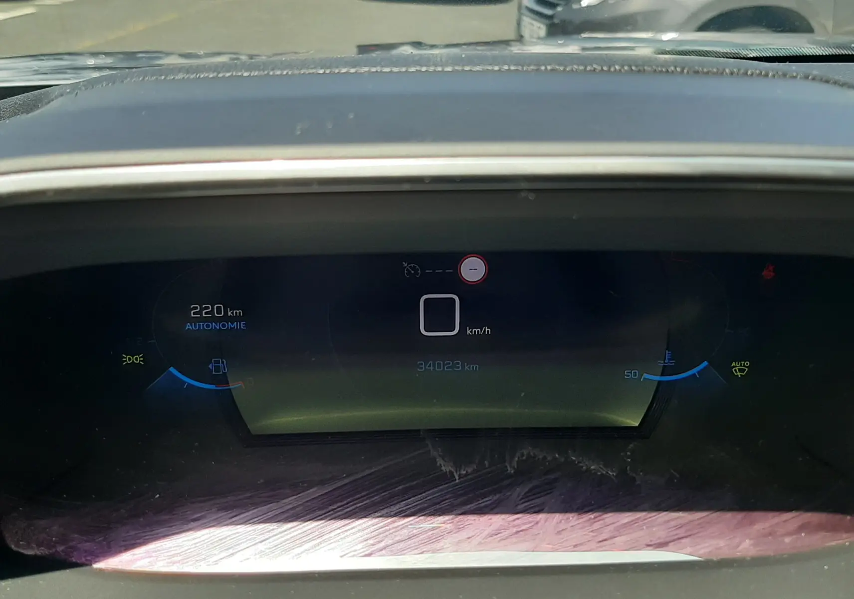 Tableau de bord numérique du Peugeot 2008 gris Artense, affichant 220 km d'autonomie et 34 023 km au compteur, vue de face.