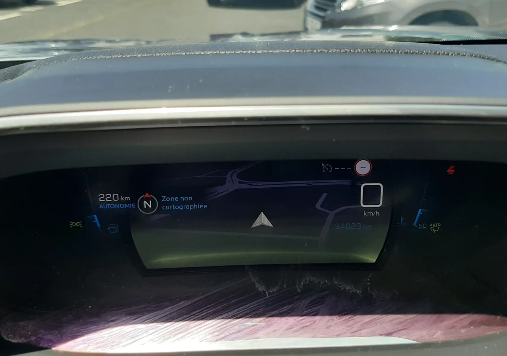 Tableau de bord numérique du Peugeot 2008 gris Artense, affichant la navigation et l'autonomie à 220 km.