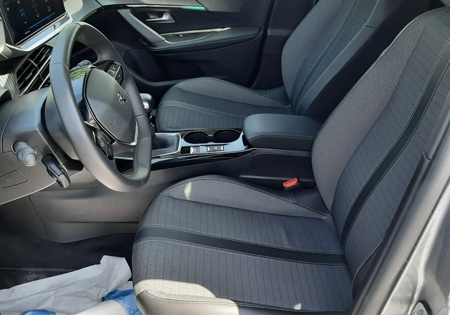 Intérieur avant droit du Peugeot 2008 2022 gris Artense, sièges tissu noir avec coutures contrastées et tableau de bord moderne.