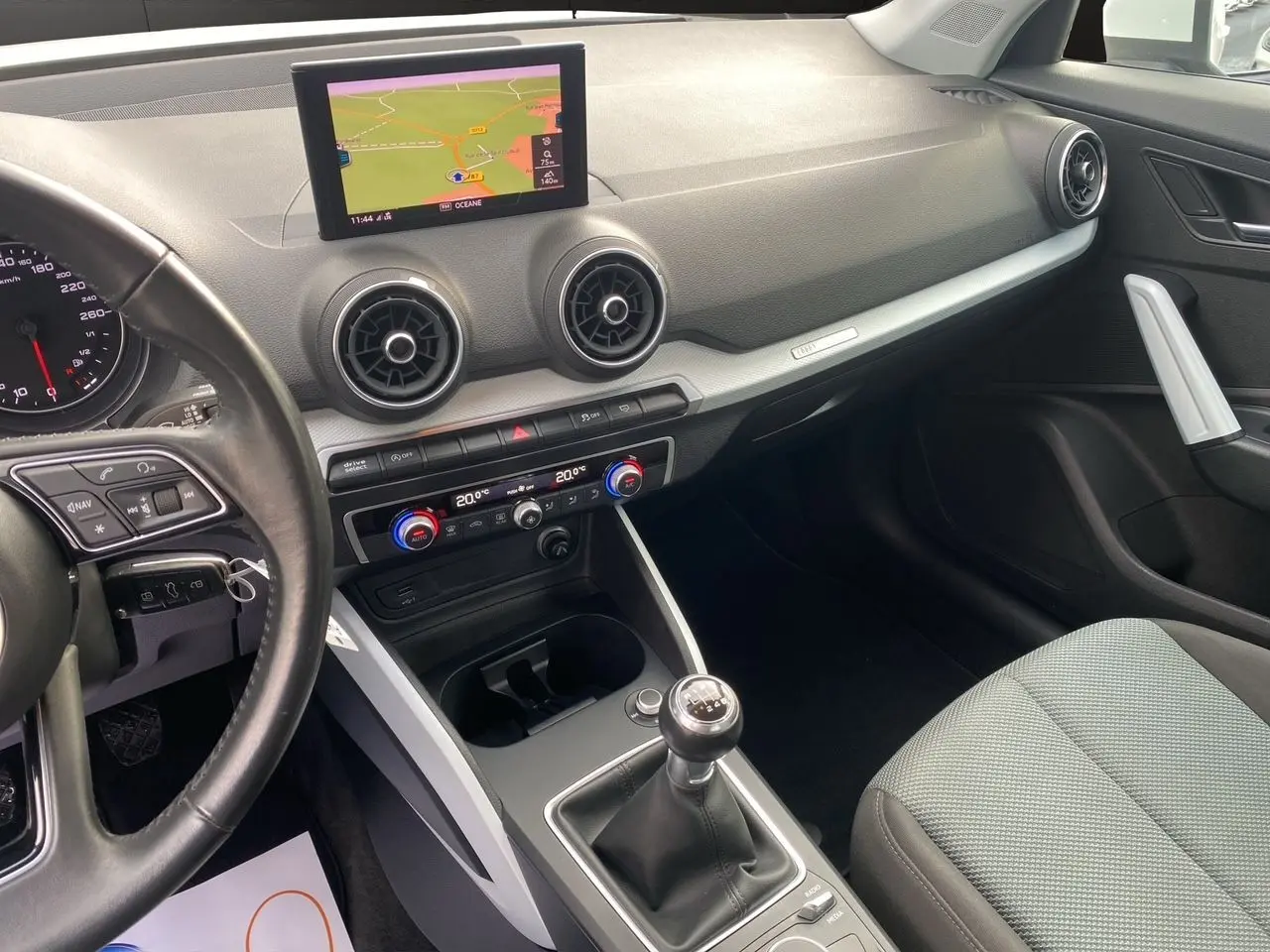 Intérieur noir et gris de l'Audi Q2 30 TDI 2019, vue côté conducteur avec écran GPS et boîte manuelle visible.