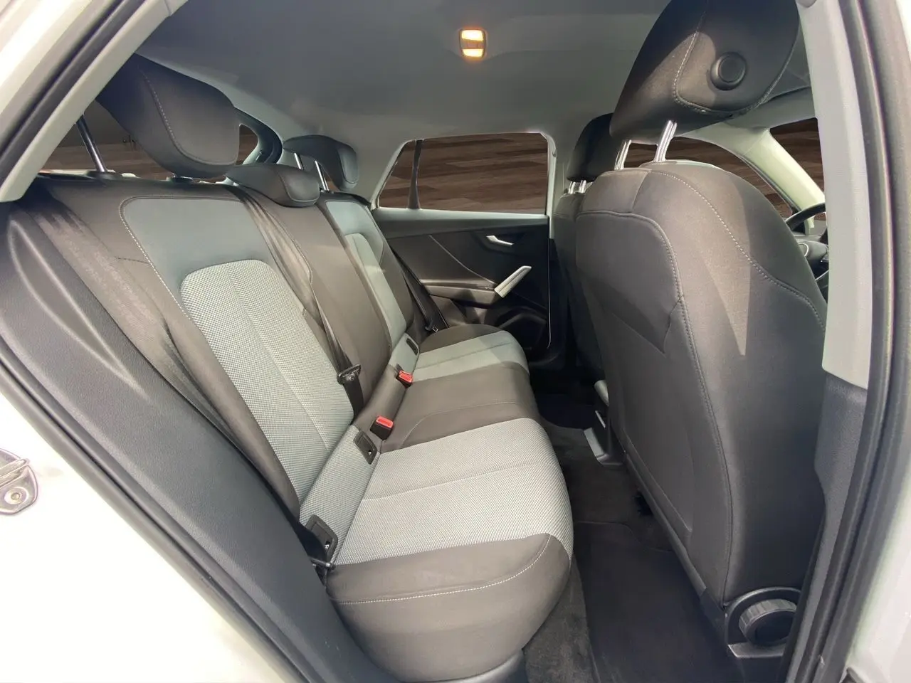 Vue intérieure arrière côté gauche de l'Audi Q2 30 TDI 116 BVM6 2019 avec sièges tissu noir et gris.