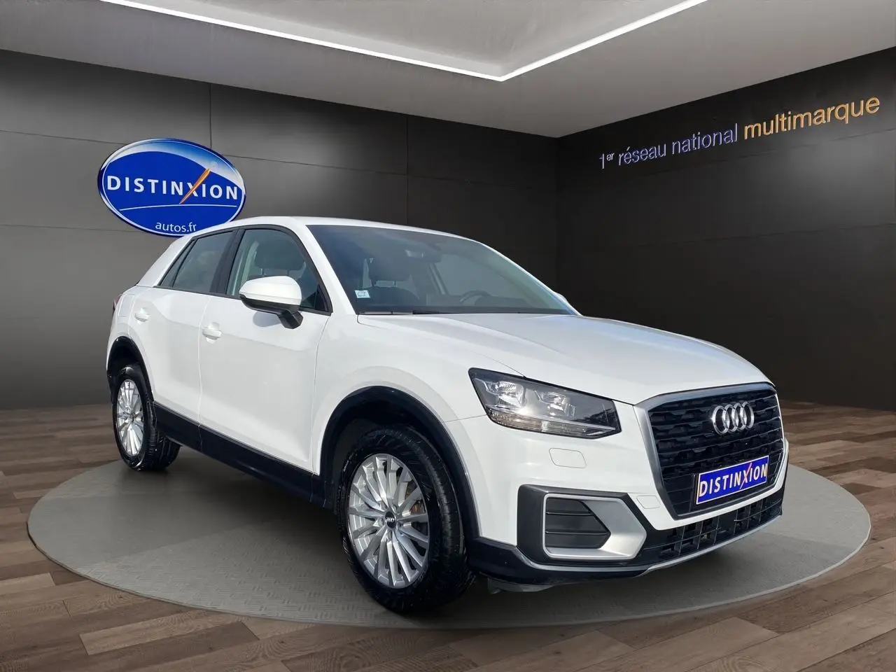 Audi Q2 blanc en 3/4 avant droit, avec calandre noire et jantes alliage visibles en showroom.