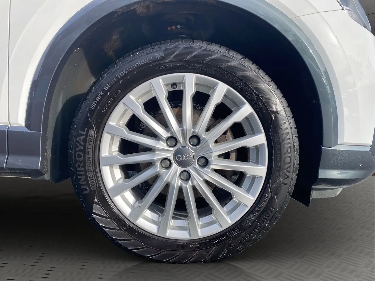 Gros plan sur la roue avant droite d'un Audi Q2 blanc de 2019 avec jante alliage argent et pneu Uniroyal.