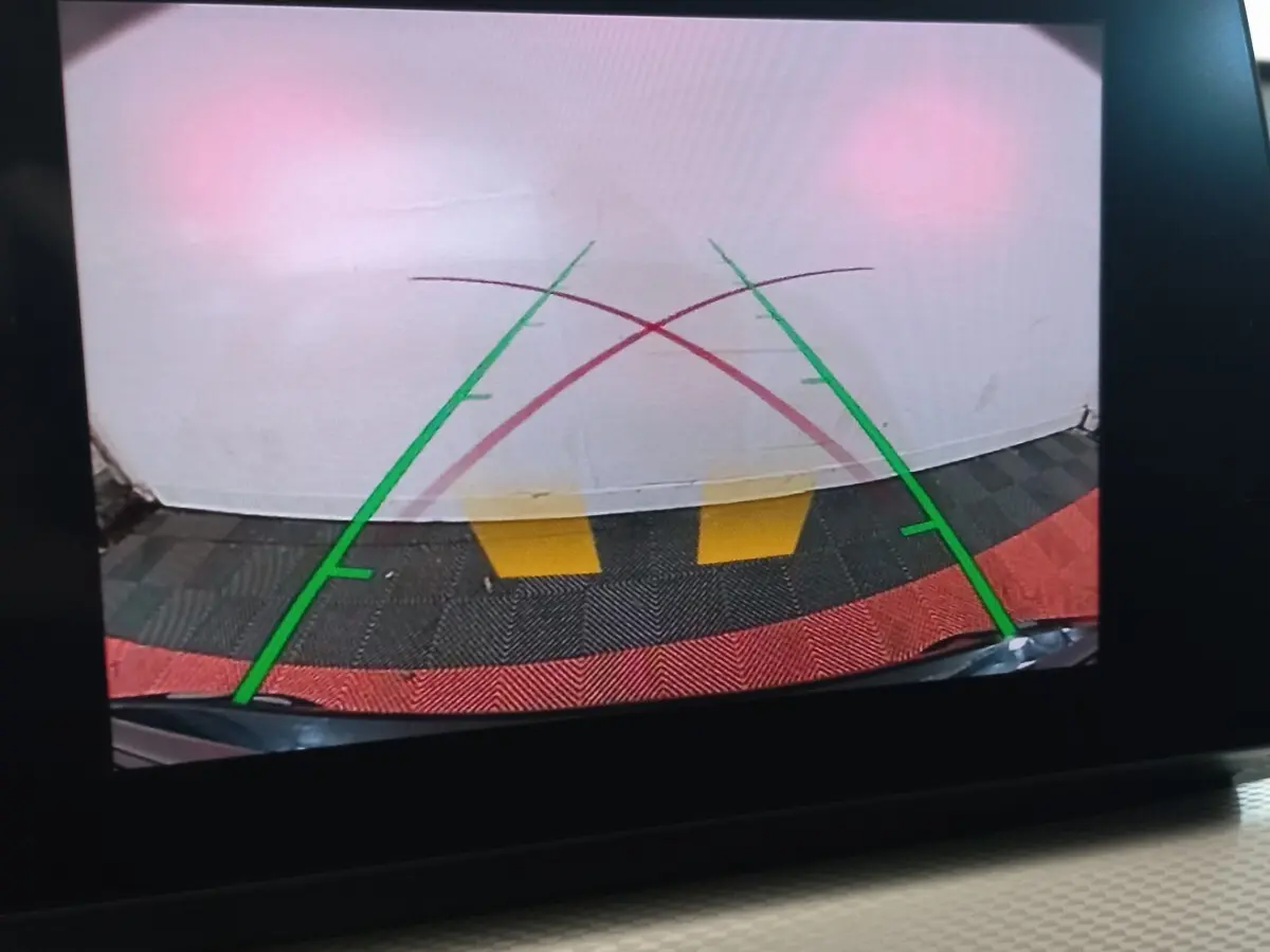 Vue caméra de recul du BMW X1 noir xDrive20d M Sport 2022, avec lignes de guidage vertes et rouges sur sol coloré.