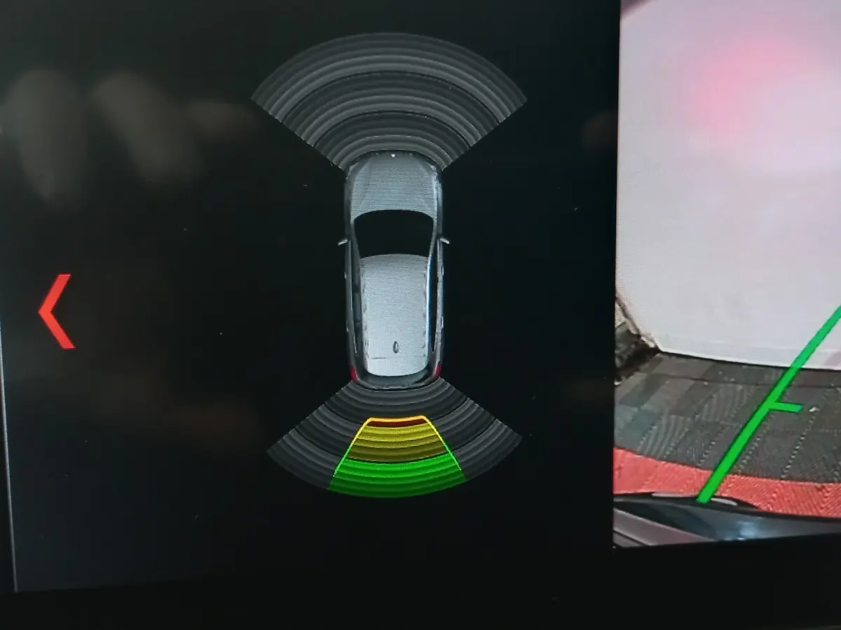 Vue de dessus sur l'écran de stationnement montrant un BMW X1 noir avec aides au stationnement activées.