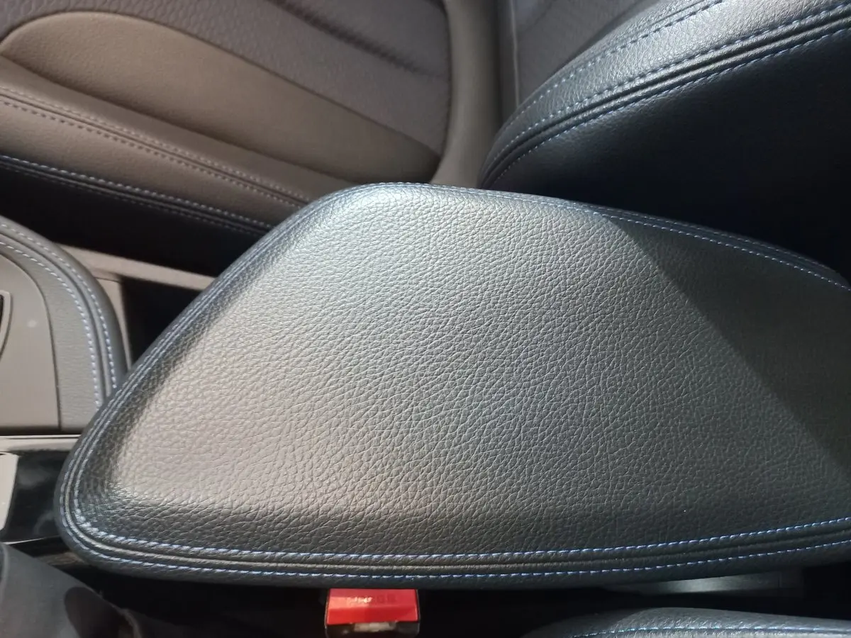Détail de l'accoudoir central en cuir noir avec surpiqûres bleues dans l'habitacle du BMW X1 xDrive20d M Sport 2022.
