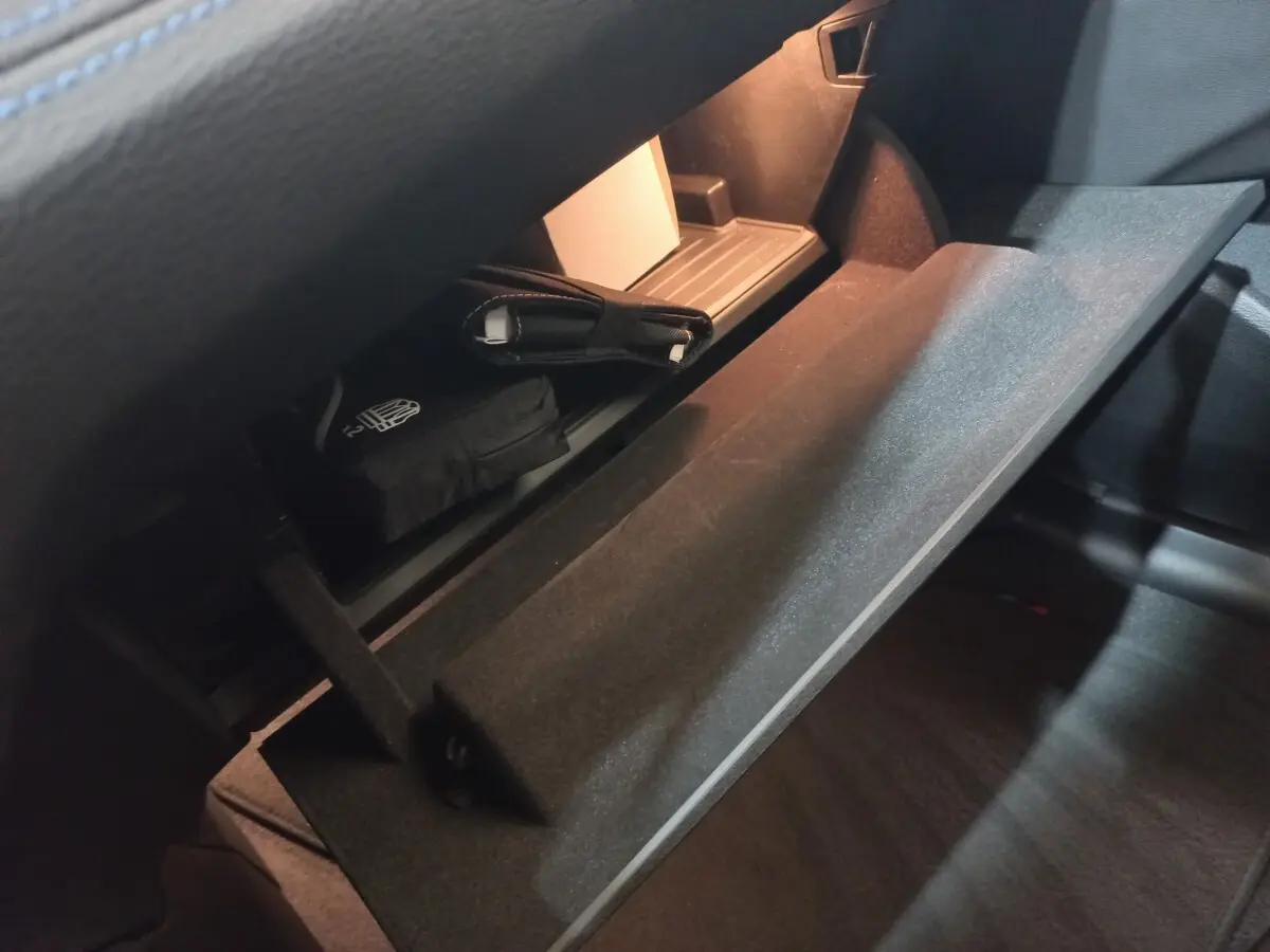 Intérieur BMW X1 xDrive20d 2022, vue sur la boîte à gants ouverte avec éclairage intérieur et objets rangés.