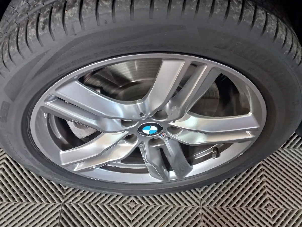 Gros plan sur la jante alliage argentée avec logo BMW d’un BMW X1 noir, vue centrée sur la roue.