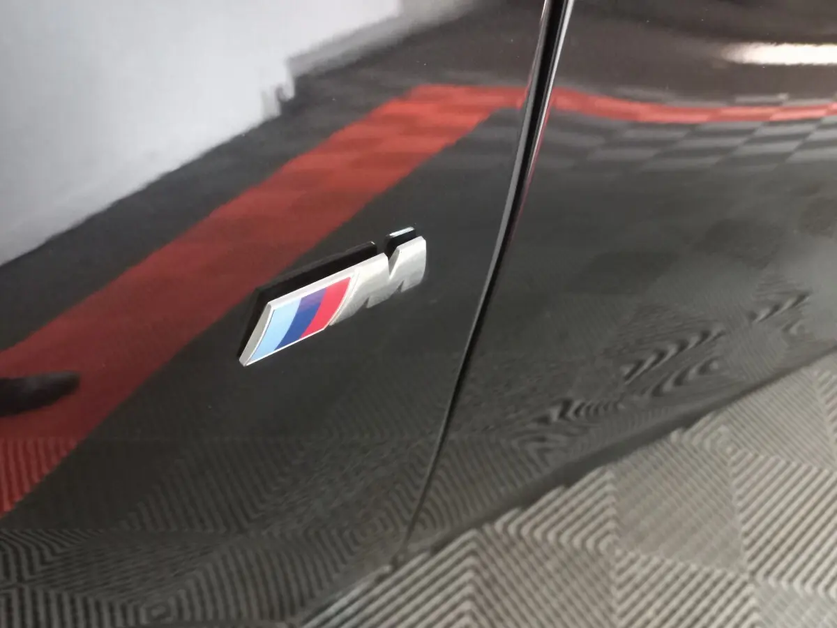 Gros plan sur l'emblème M sur la porte noire brillante d'une BMW X1 xDrive20d M Sport 2022.