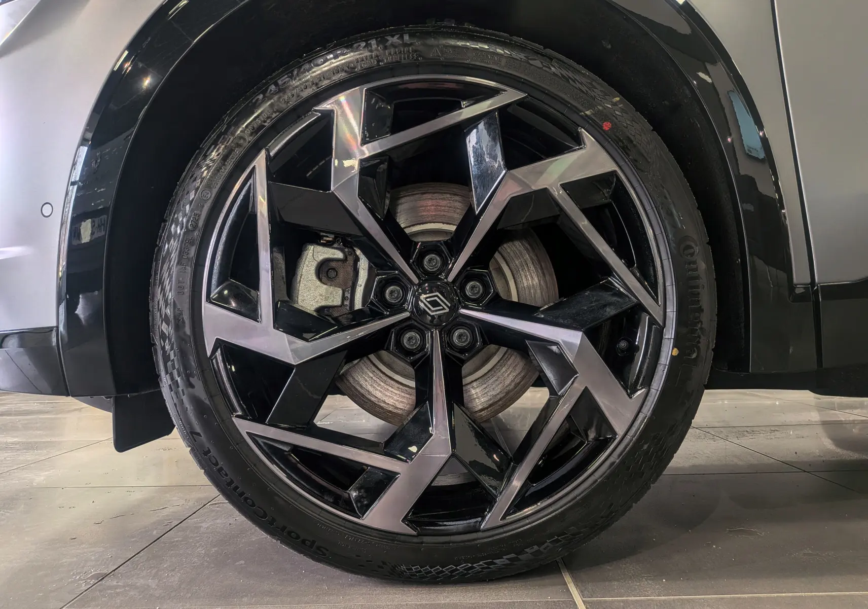 Gros plan sur la roue avant droite du Renault Rafale gris Schiste Satin, mettant en valeur la jante biton noire et argentée au design anguleux.