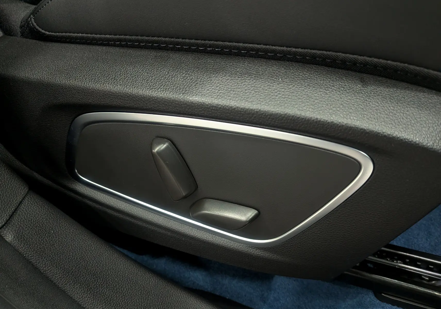 Gros plan sur les commandes électriques de réglage du siège en cuir noir dans l’habitacle du Renault Rafale gris Schiste Satin.