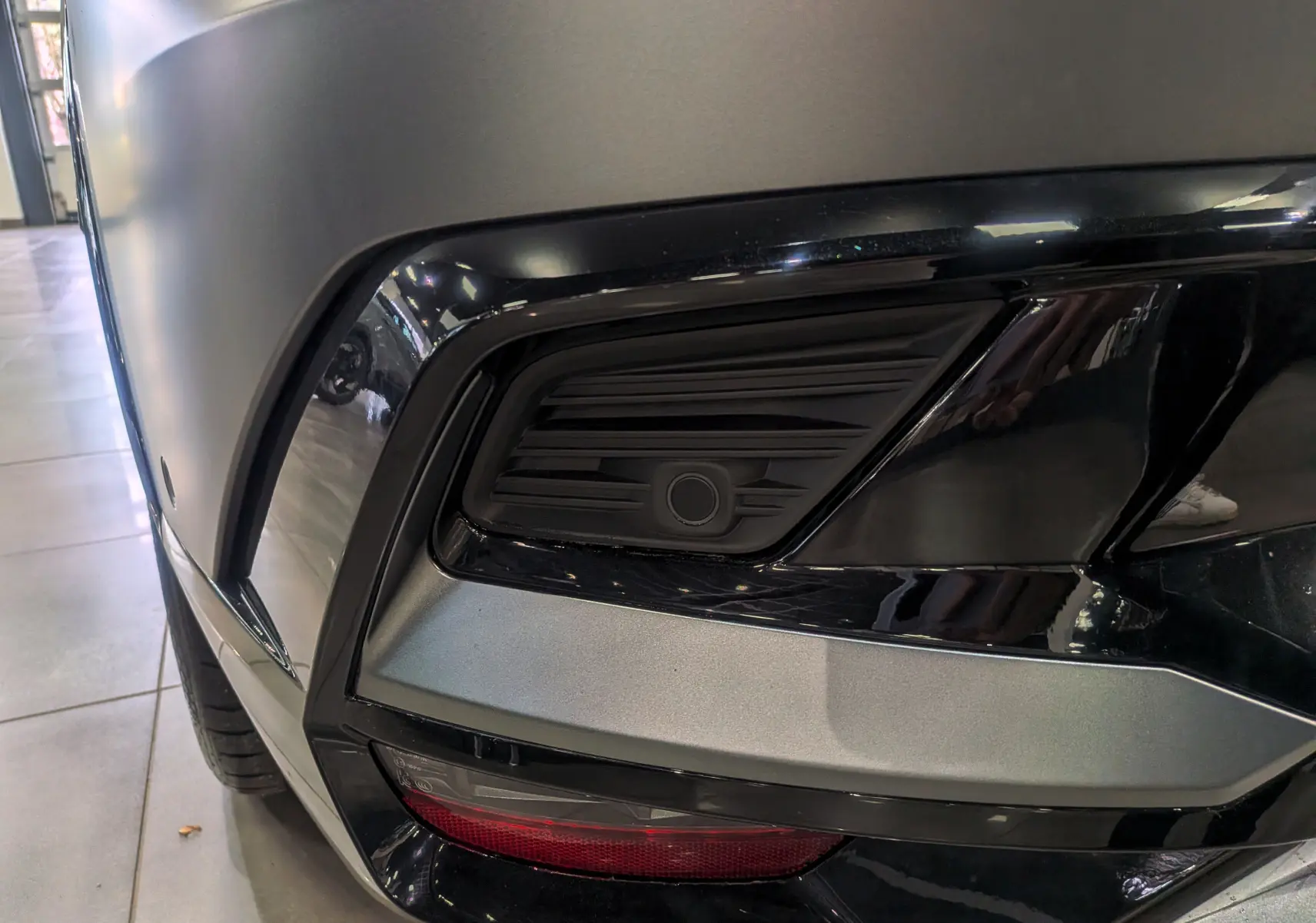 Gros plan sur le pare-chocs avant droit gris Schiste Satin du Renault Rafale 2025 avec capteur de stationnement intégré.