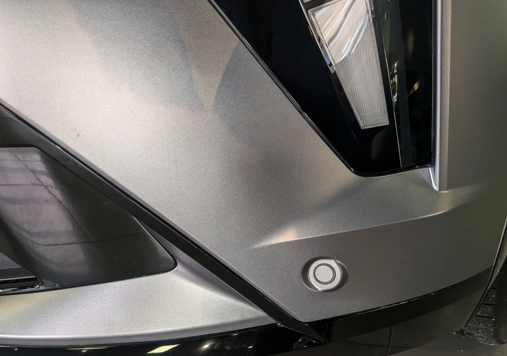 Détail du pare-chocs avant gris schiste satin du Renault Rafale 2025 avec capteur de stationnement et insert noir brillant.