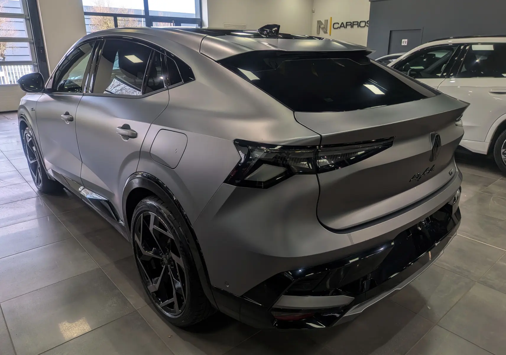 Vue 3/4 arrière droite du Renault Rafale gris Schiste Satin avec jantes noires et toit noir en intérieur showroom.