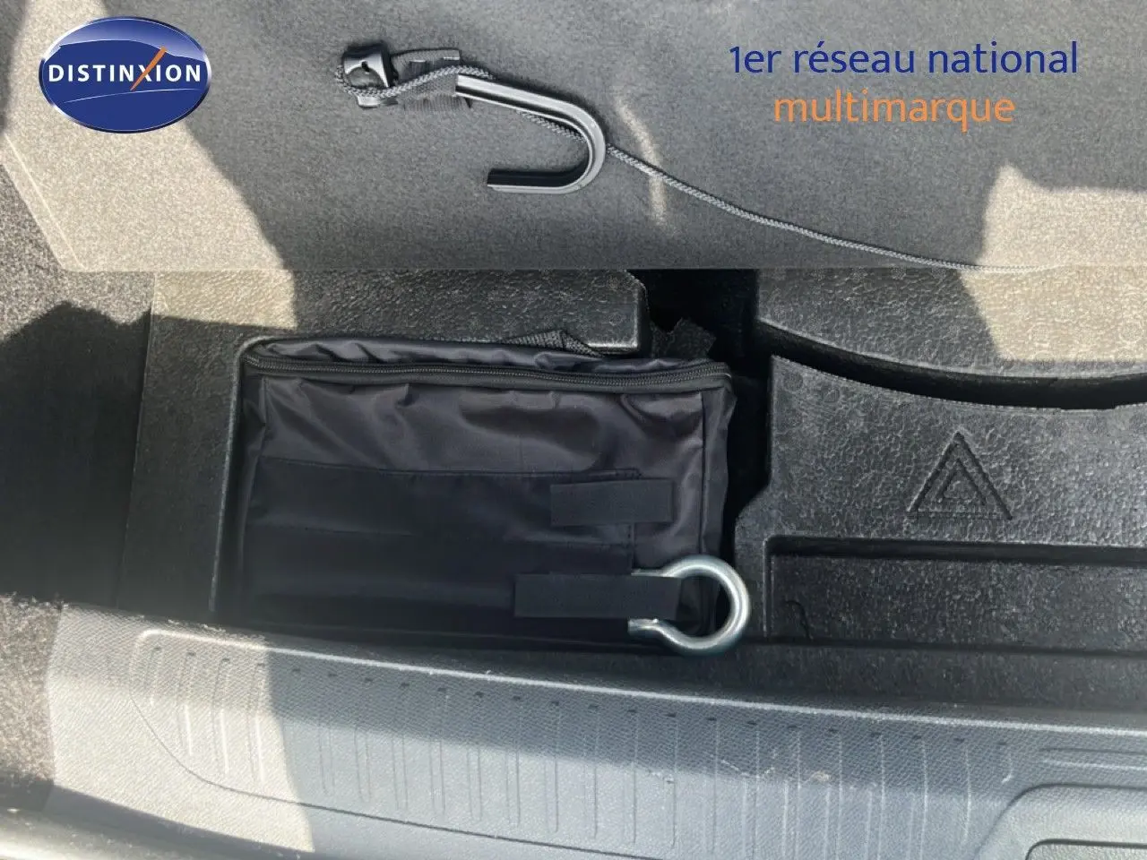 Vue rapprochée du coffre de la Peugeot 408 noir métal, montrant un kit de secours et un crochet de remorquage.
