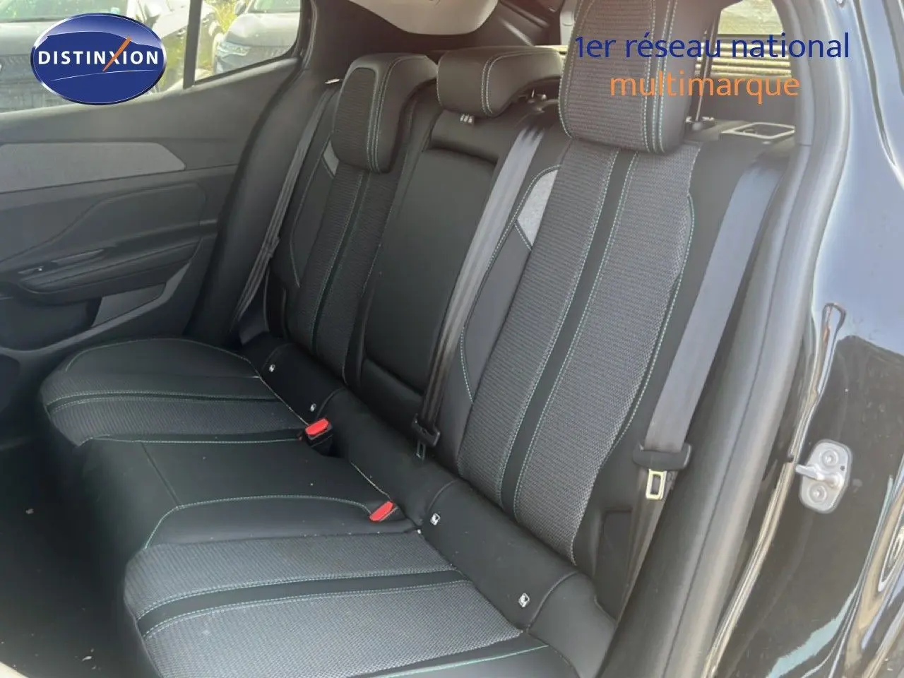 Vue intérieure sur la banquette arrière d’une Peugeot 408 noire métal, sièges en tissu et cuir avec surpiqûres contrastées.