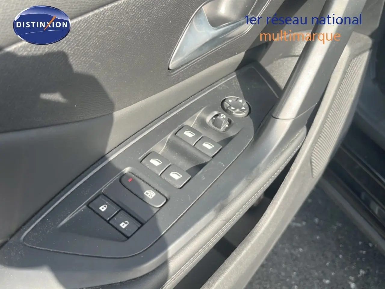 Gros plan sur la commande des vitres et des rétroviseurs côté conducteur d’une Peugeot 408 noire métal, intérieur gris.